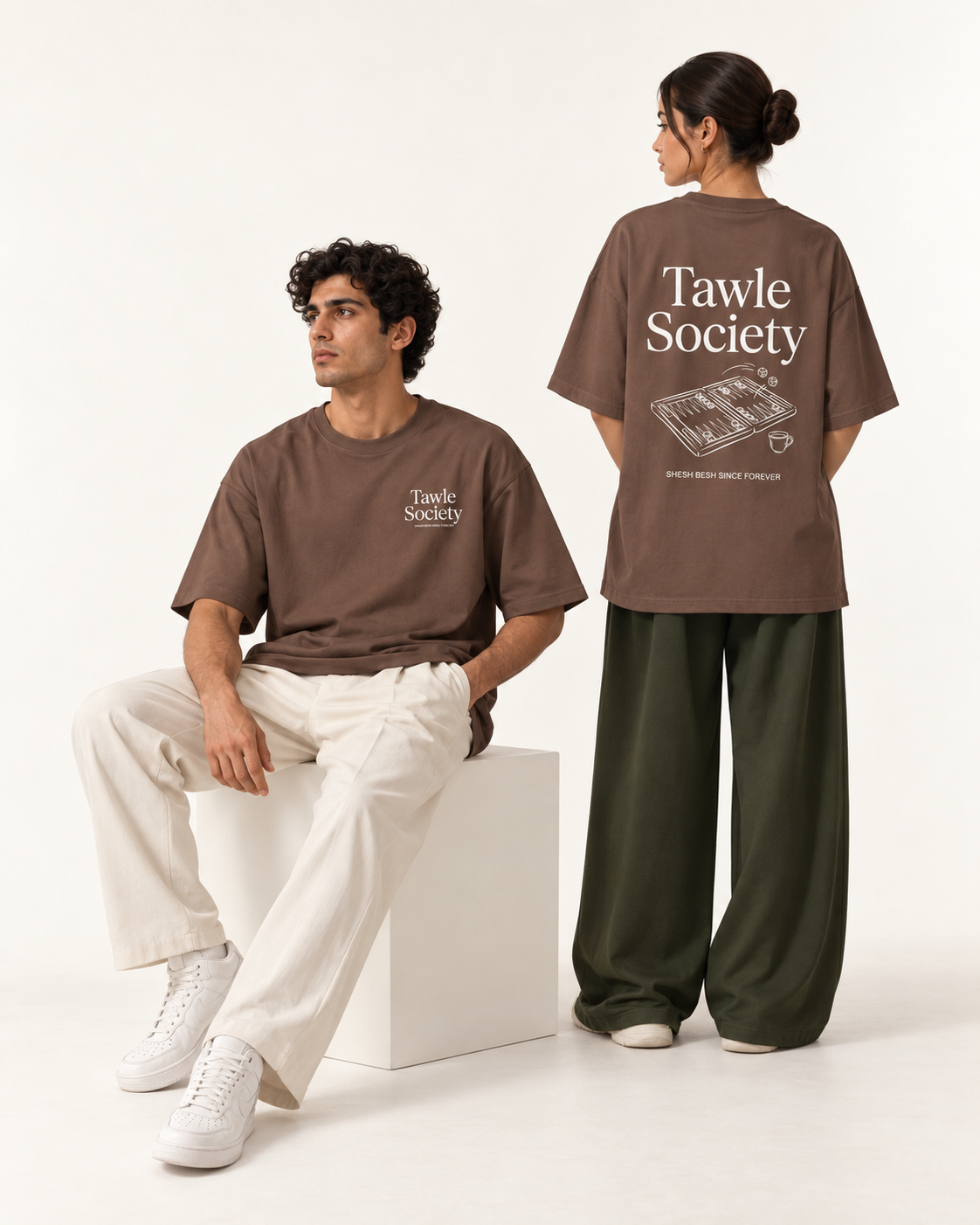 Two models showing the front and backgammon back graphic on brown Monani Tawle Society T-shirts
