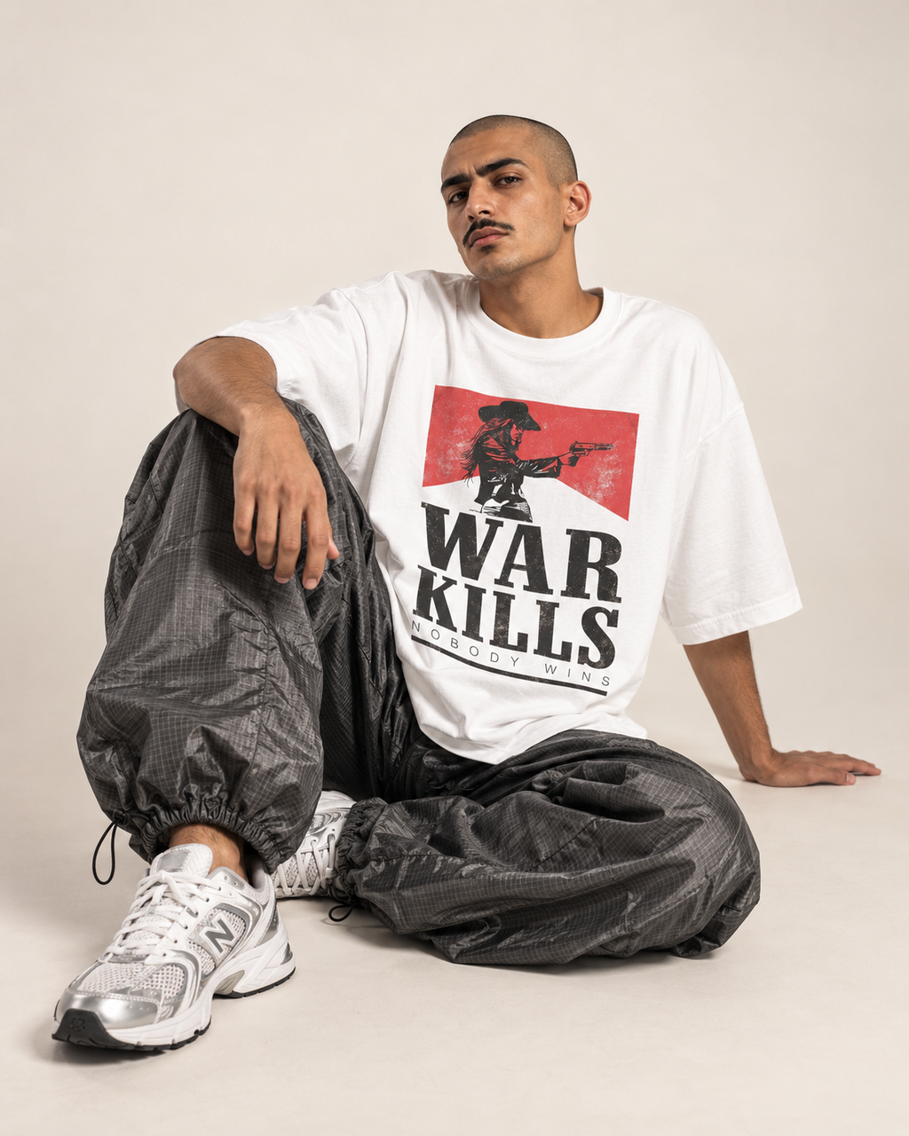 Seated model wearing a white Monani T-shirt with a black and red War Kills front graphic