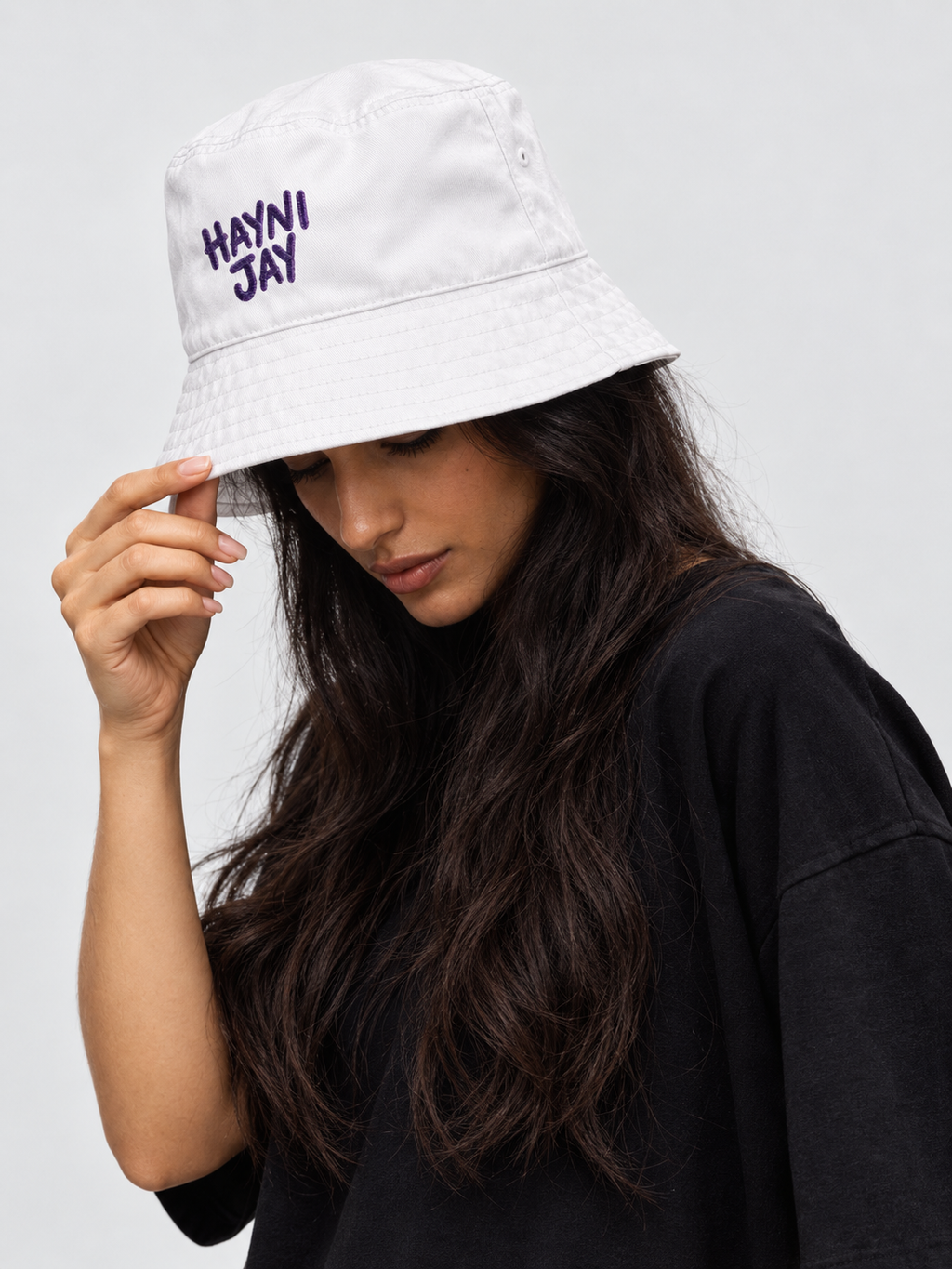 Model wearing the Monani Hayni Jay white bucket hat with hand on brim