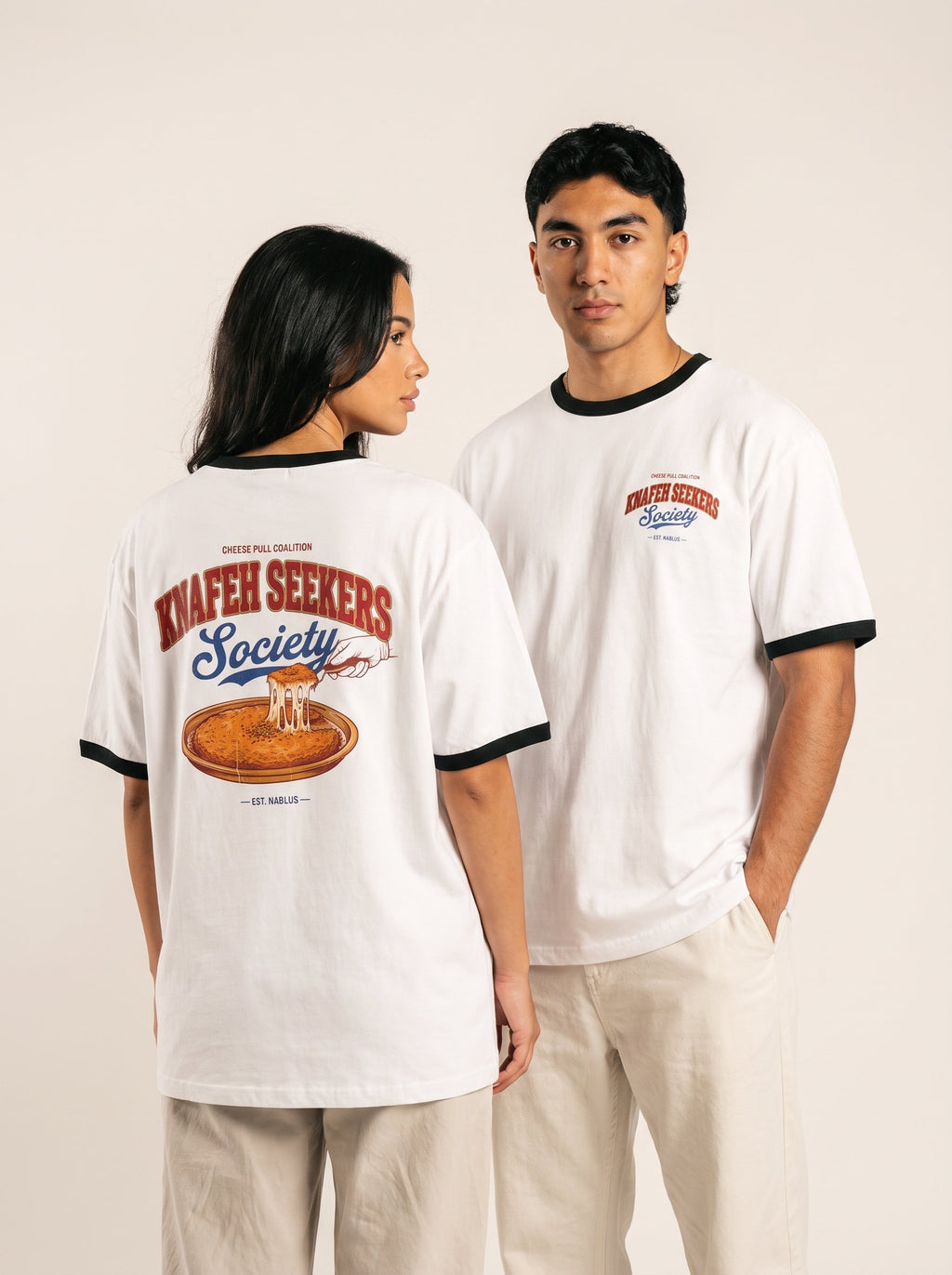 Two models showing the front and dessert graphic on a white Monani Knafeh Seekers Society ringer T-shirt