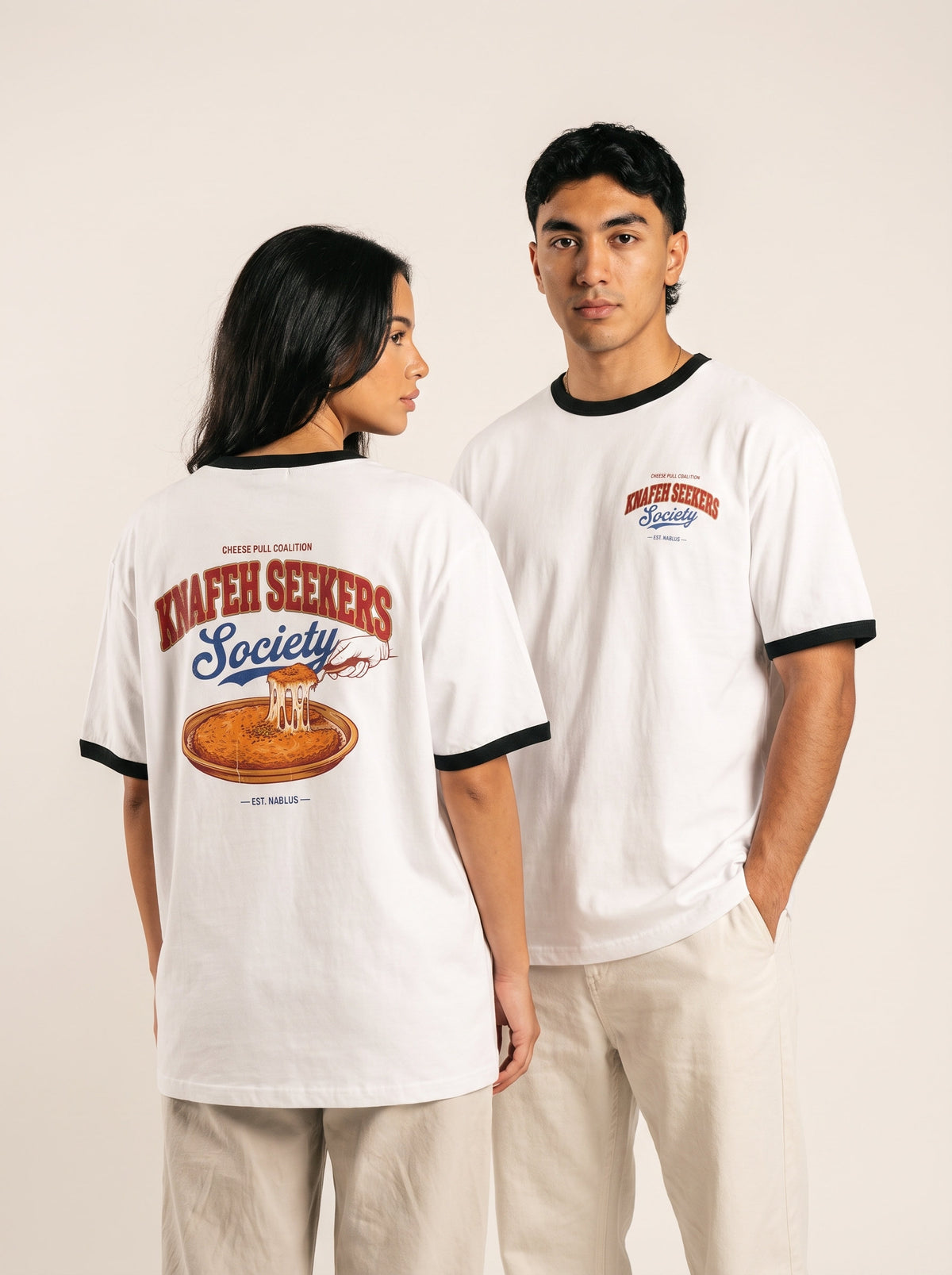 Two models showing the front and dessert graphic on a white Monani Knafeh Seekers Society ringer T-shirt